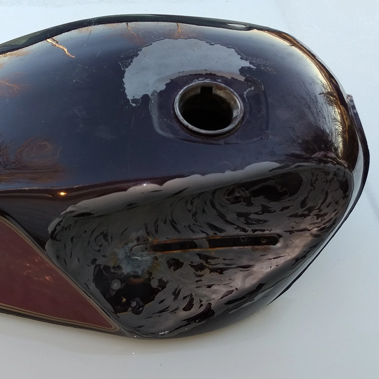 Switching the handlebars to clip-ons meant they no longer cleared the gas tank. I hammered in both sides of the tank to make room.