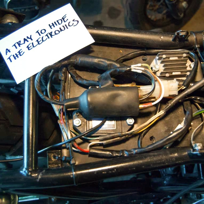 I cut the tray from sheet metal and mounted it to the frame under the seat with zip ties.