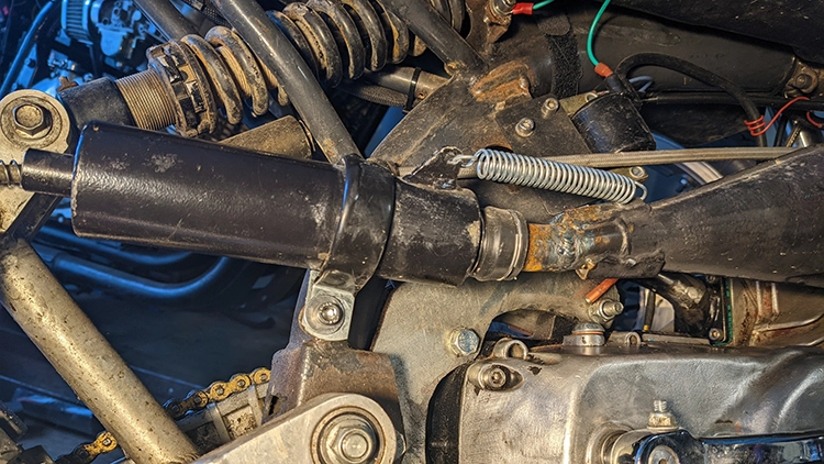 The silencer kept vibrating off the bike. This final solution included a dirtbike style soft joint between silencer and exhaust chamber to absorb vibrations, and a strap to hold the silencer on after it inevitably worked its way free.